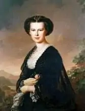 Retrato pintado de una mujer con el pelo oscuro recogido, vestida con un vestido oscuro con cuello de encaje blanco, sosteniendo un perro pequeño y mirando un paisaje pintoresco al fondo.
