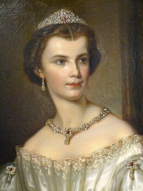Gemaltes Porträt einer jungen Frau, die ein juwelenbesetztes Diadem, eine passende Halskette, Ohrringe und ein elegantes, schulterfreies weißes Kleid trägt und mit heiterem Gesichtsausdruck leicht zur Seite blickt.